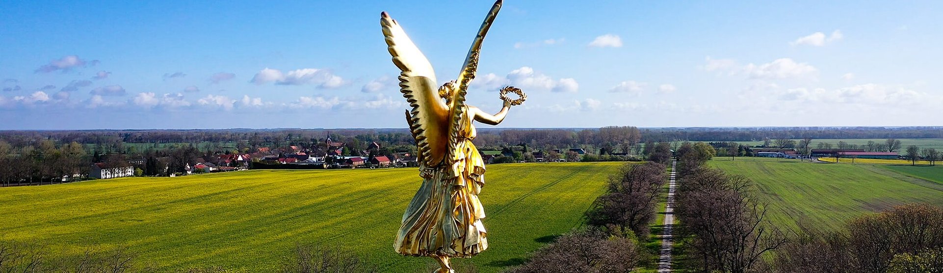eine goldene Statue in der Höhe mit Feld im Hintergrund