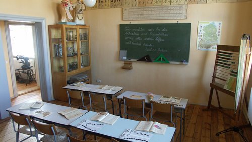 ein Klassenzimmer mit Tafel, Stühlen und Tischen